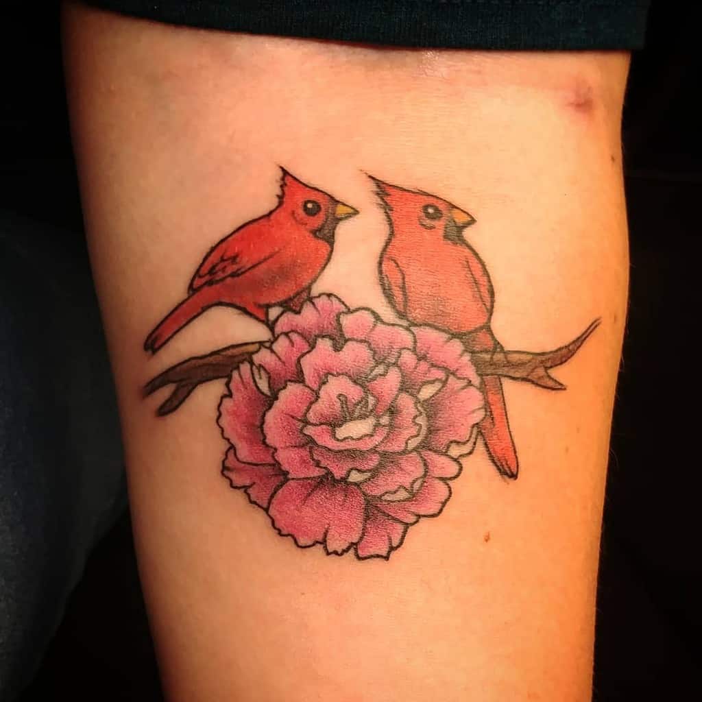 Tattoo of two red cardinals on a branch with a large pink carnation