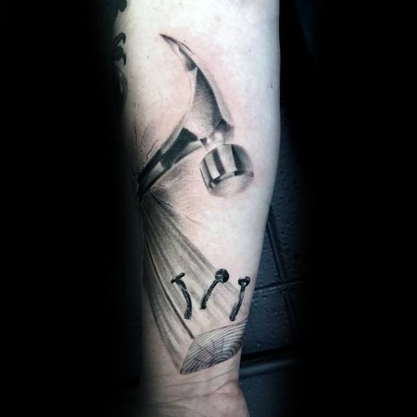 Realistic tattoo of a hammer driving nails into wood, symbolizing strength, craftsmanship, and dedication to woodworking and construction.