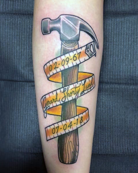 Colorful tattoo of a hammer wrapped in a measuring tape with dates and a name, symbolizing craftsmanship, legacy, and remembrance.