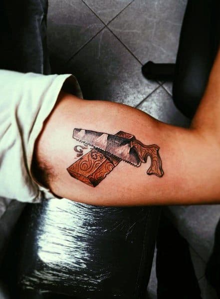 Tattoo of a hand saw cutting through a wooden block, symbolizing craftsmanship, precision, and a passion for woodworking.