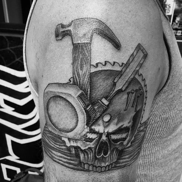 Black and gray tattoo featuring a hammer, chisel, saw blade, and skull, symbolizing strength, craftsmanship, and dedication to the trade.