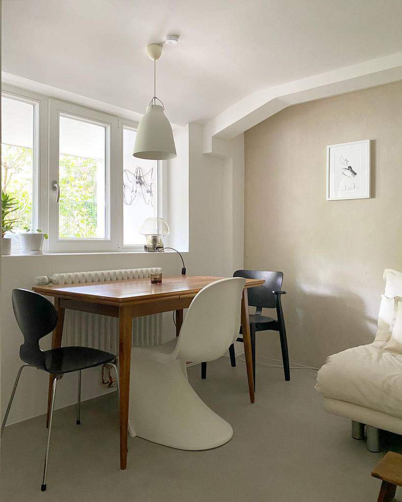 Minimalist dining nook with wooden table, modern chairs, and soft neutral tones.