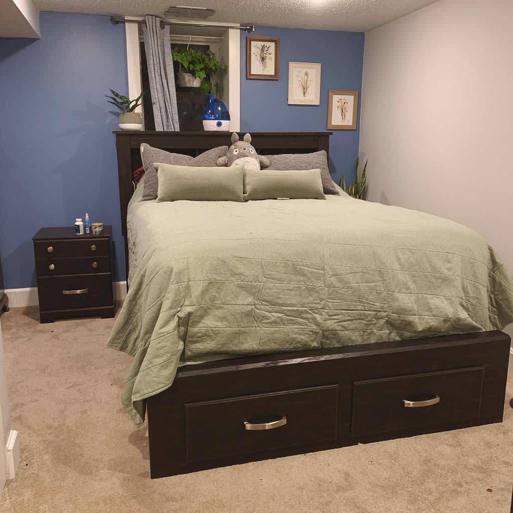 Basement bedroom with dark wood furniture, blue feature wall, and green bedding.