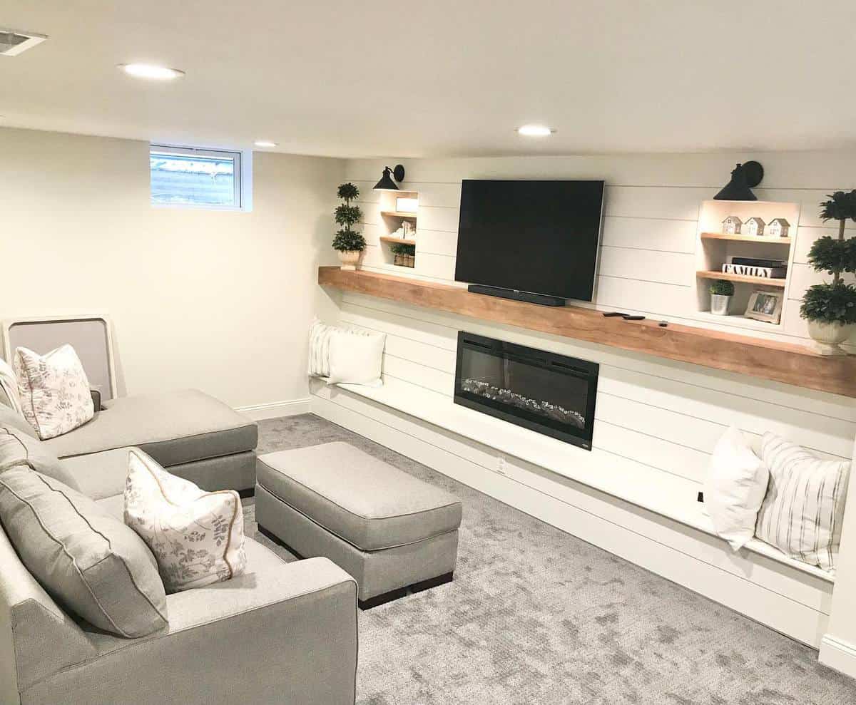 Contemporary lounge room with built-in fireplace, mounted TV, grey sectional sofa, and decorative shelving.