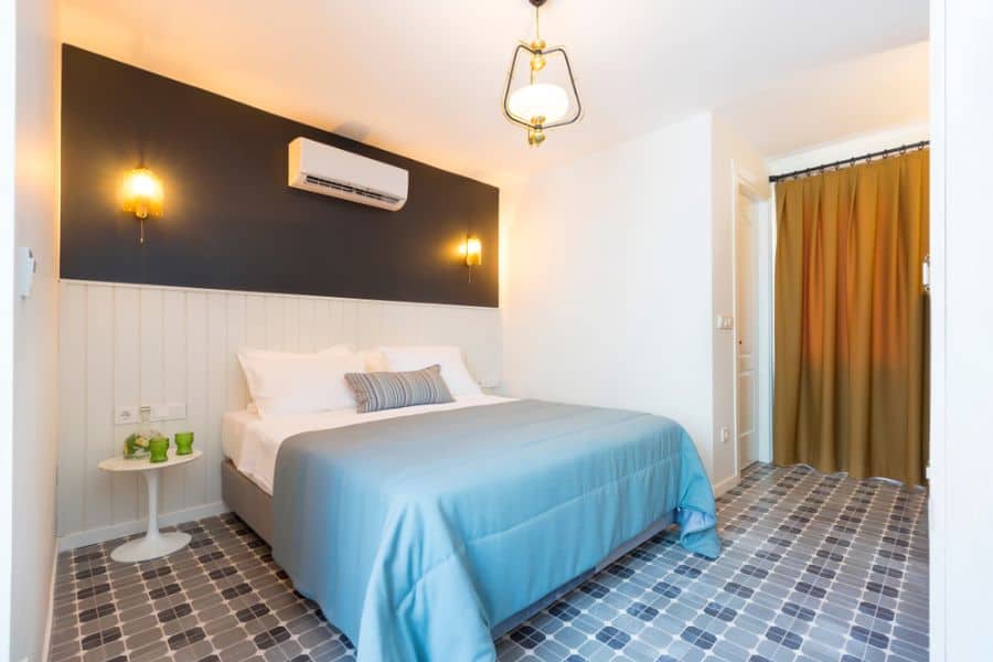 Cozy bedroom with blue bedding, dark accent wall, and checkered tile flooring.