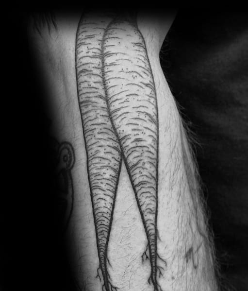 Black and gray tattoo of two long, detailed carrots on the leg, featuring fine line shading and realistic texture for a bold organic look.