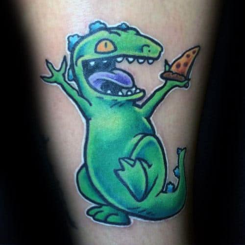 Fun and colorful tattoo of Reptar from Rugrats, joyfully holding a slice of pizza with a wide open mouth and excited expression.