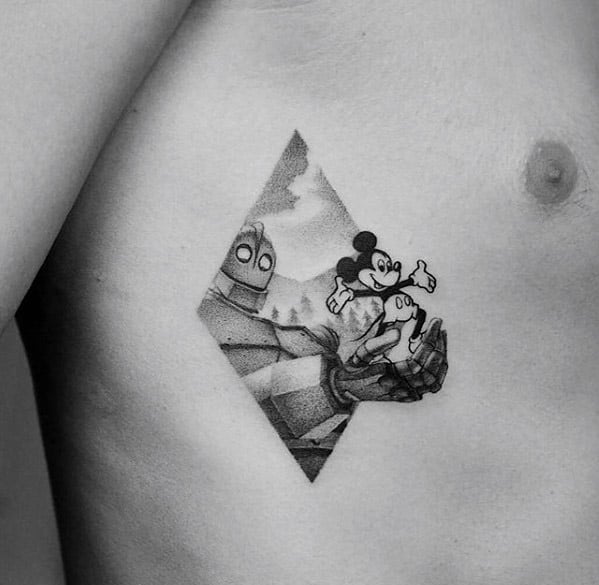 Black and grey tattoo of the Iron Giant holding classic Mickey Mouse, framed in a diamond shape with a mountain background.