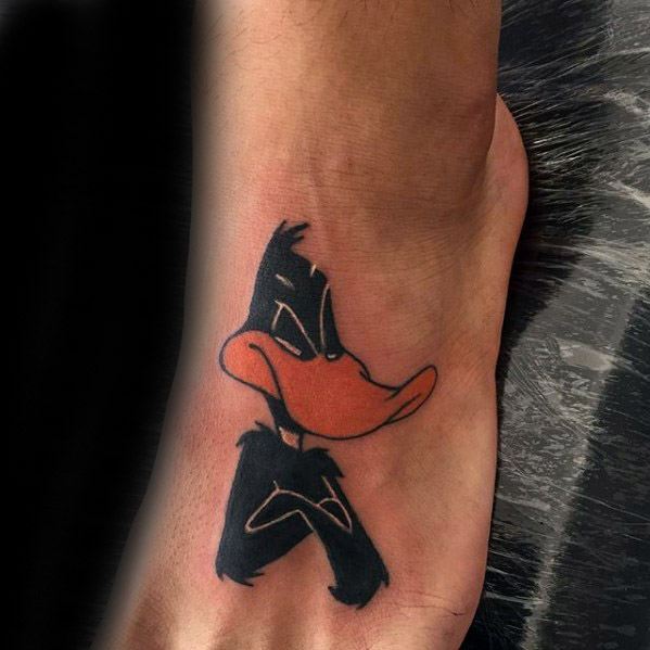 Simple and bold tattoo of Daffy Duck with crossed arms and a grumpy expression placed on the top of the foot.