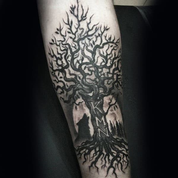 Forearm tattoo of a detailed tree with roots, wolf silhouette, and initials "KMN"
