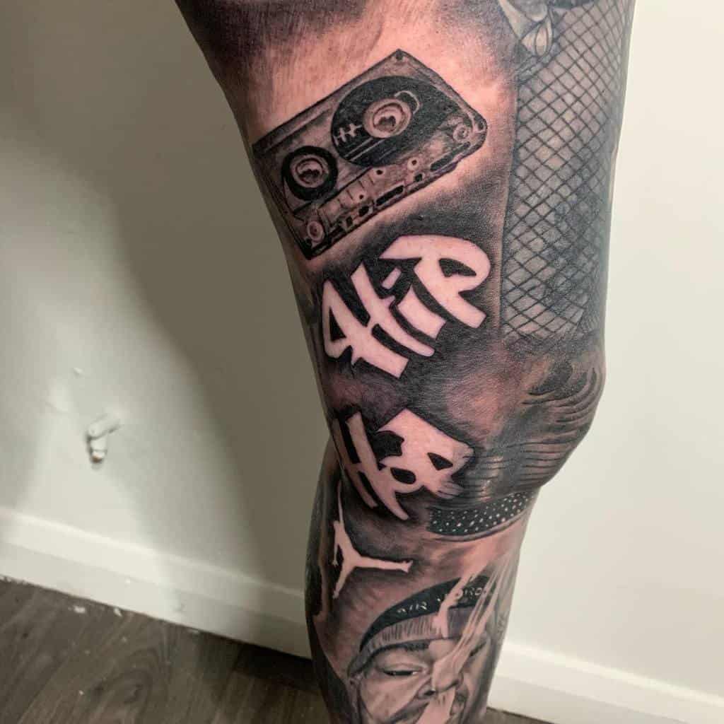 Black and grey tattoo leg sleeve with a retro cassette tape, the word 'HIP HOP,' a Jordan logo, a barbed wire and a man wearing a hat smoking