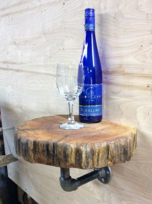 Wine bottle and glass on a rustic wood shelf with pipe bracket against a wooden wall
