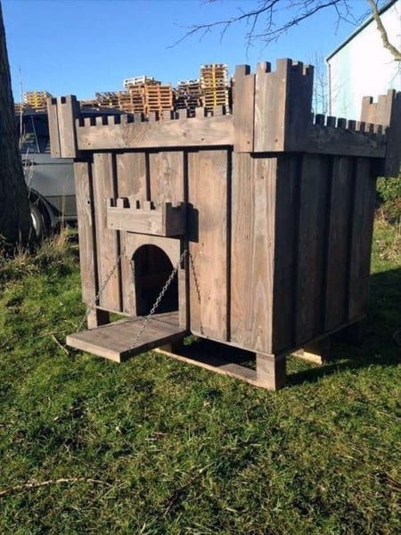 A wooden doghouse for your dog, styled like a medieval castle with a drawbridge entrance on grass
