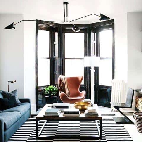 Modern living room with a bold black and white striped area rug, grey sofa, and accent chair.