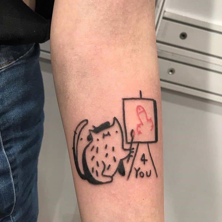 A humorous black ink tattoo of a cat painting a crude drawing on a canvas with the text '4 You' underneath, placed on the forearm.
