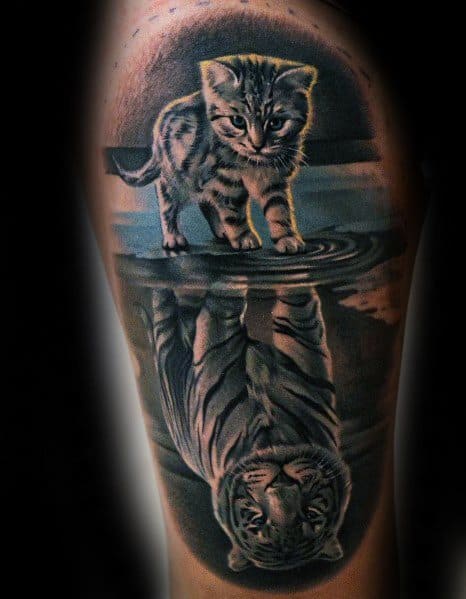 Realistic tattoo of a kitten looking into water, reflecting a tiger, symbolizing strength and potential in a bold design.