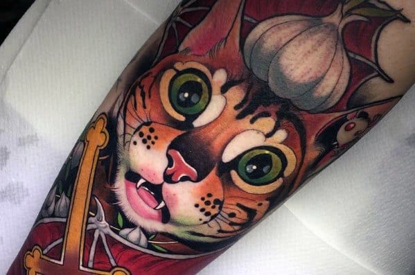 Vibrant neo-traditional cat tattoo with wide eyes, gothic elements, and rich colors, creating a bold and striking design.