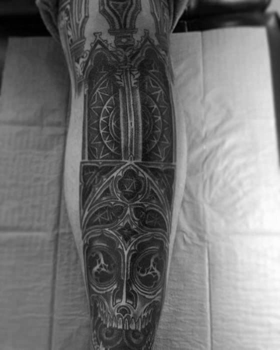 Full leg tattoo with gothic cathedral architecture, pointed arches, stained glass patterns, and a skull integrated at the base.