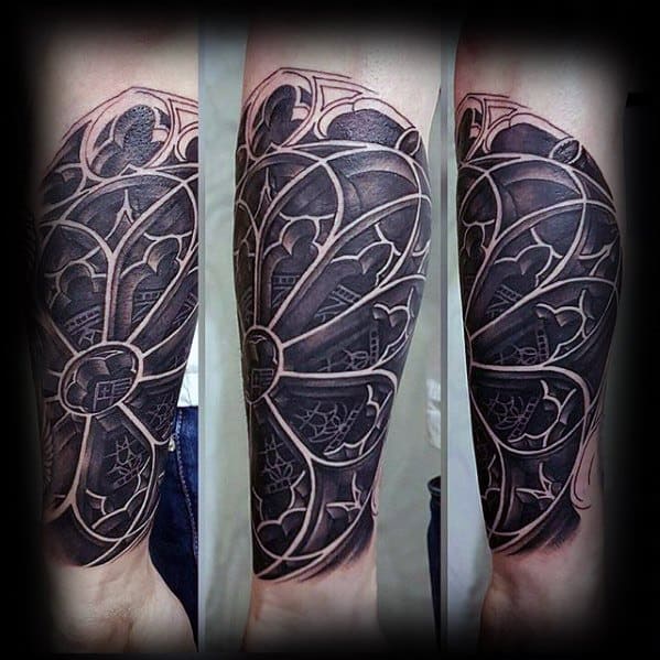 Half-sleeve tattoo of a gothic stained glass window with bold outlines, deep shading, and intricate architectural patterns.