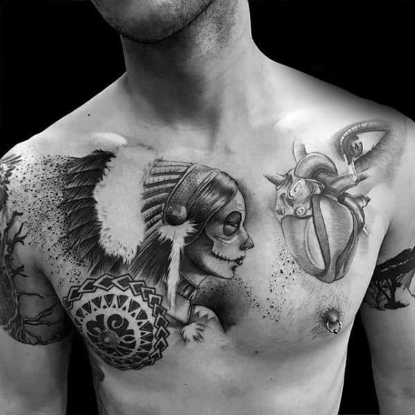 La Catrina chest tattoo of a woman in a feathered headdress with sugar skull makeup, paired with an anatomical heart on the opposite side.