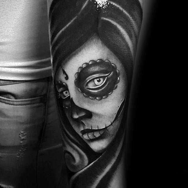 La Catrina tattoo of a mysterious woman with sugar skull makeup and flowing hair, shaded in bold black and grey tones.
