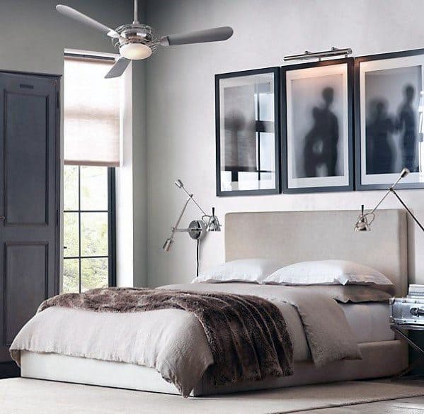Modern bedroom with framed wall art ceiling fan and adjustable reading lamps.