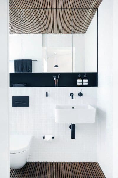 Modern bathroom with wood panel ceiling, mirrored cabinets, white tile walls, and black fixtures.