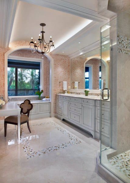 Elegant bathroom with chandelier, LED strip lighting, marble floors, and large vanity.