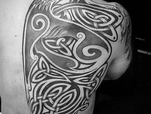 Black and grey Celtic tattoo covering the shoulder and upper back, featuring intricate knotwork, bold lines, and interwoven patterns.