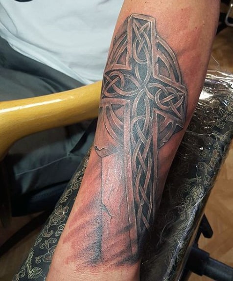Forearm tattoo showcasing a Celtic cross with detailed knot patterns