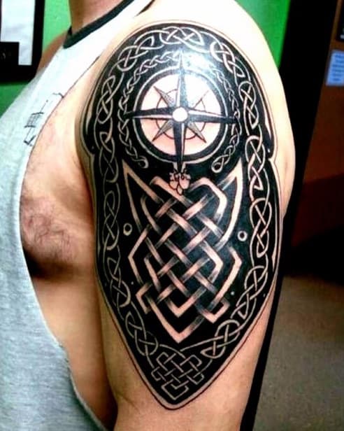 Man with intricate Celtic knot tattoo and compass design on upper arm