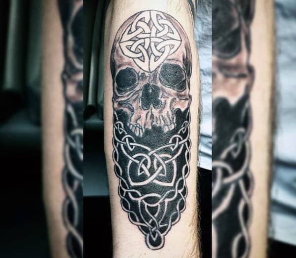 Tattoo of a skull with intricate Celtic knot patterns on an arm