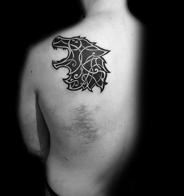 Celtic wolf head tattoo on upper back with bold black fill and white knotwork forming a fierce, roaring silhouette.