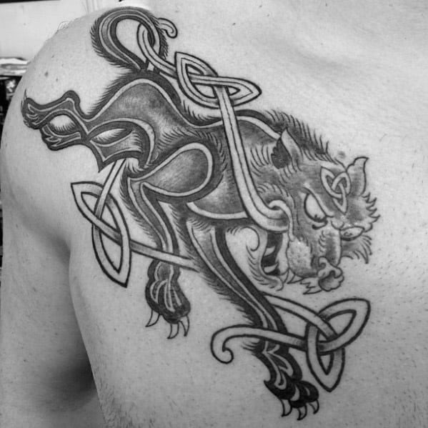 Celtic wolf tattoo on upper chest with fierce expression, bold lines, and knotted patterns wrapping through the body.