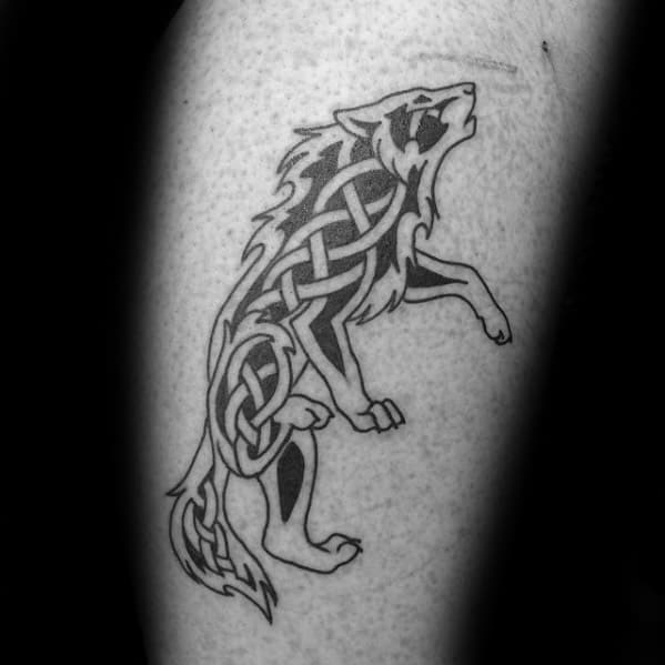 Celtic wolf tattoo on leg with black knotwork flowing through the body of a standing wolf in a bold, stylized pose.