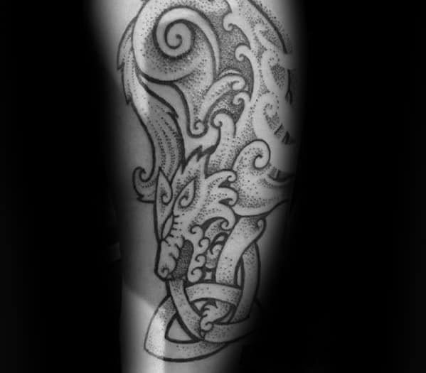 Celtic wolf tattoo with dotwork shading and swirling patterns, featuring a stylized wolf head and knotted design on the forearm.