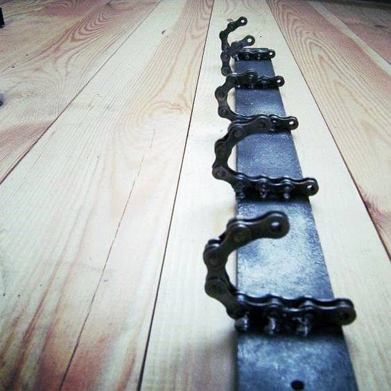 A row of metal bike chain links attached to a rectangular base on wooden floorboards