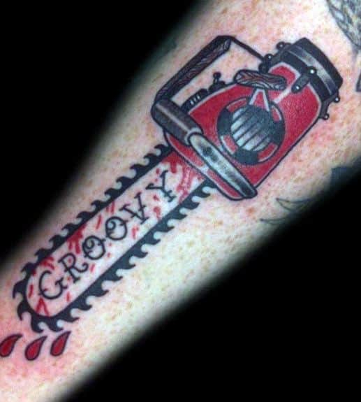 Red and black chainsaw tattoo with the word "GROOVY" on the blade and dripping blood, inspired by horror pop culture.