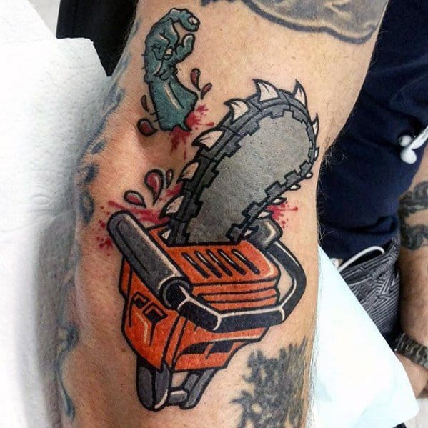 Bold cartoon-style tattoo of an orange chainsaw with blood splatter and a severed zombie hand, blending horror and comic themes.