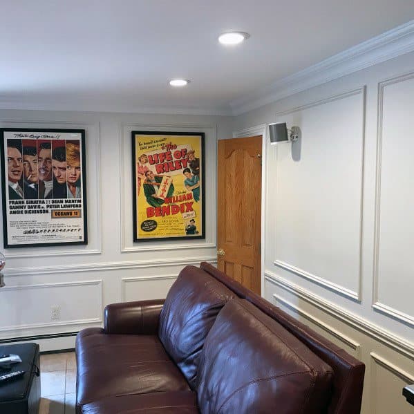 Cozy home theater with white chair rail molding, vintage movie posters, and a leather sofa for a cinematic vibe
