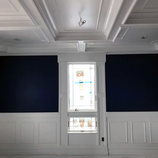 Elegant dining room featuring white chair rail molding, deep blue walls, and a coffered ceiling for a sophisticated look
