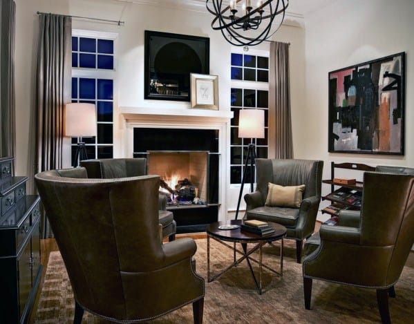 Cozy man cave featuring leather chairs, a fireplace, abstract art, and warm lighting