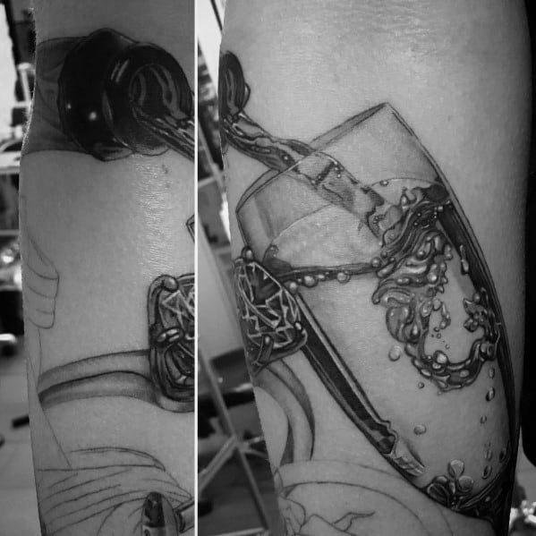 Realistic black and grey tattoo of champagne being poured into a glass, capturing detailed bubbles and splashing liquid.