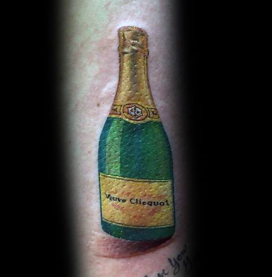 Tattoo of a Veuve Clicquot champagne bottle on skin, featuring detailed labeling and a realistic design.