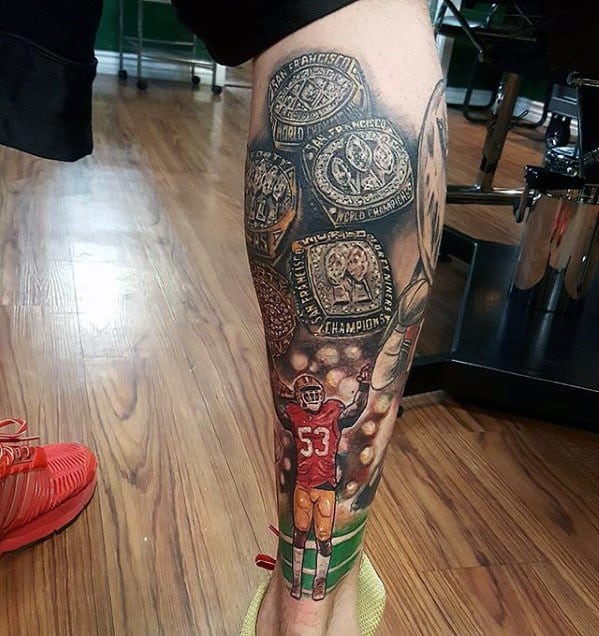 Detailed leg tattoo featuring a football player in a 49ers uniform, championship rings, and stadium lights, blending color and blackwork elements.