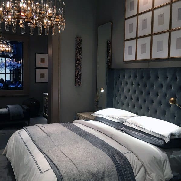 Luxurious bedroom with tufted headboard, elegant chandelier, and framed wall art.