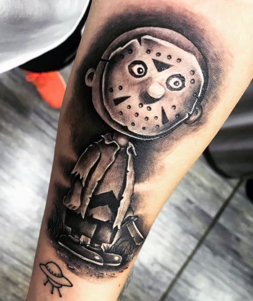 Dark and eerie Charlie Brown tattoo with a Jason Voorhees-style hockey mask and tattered outfit, blending horror with Peanuts nostalgia.