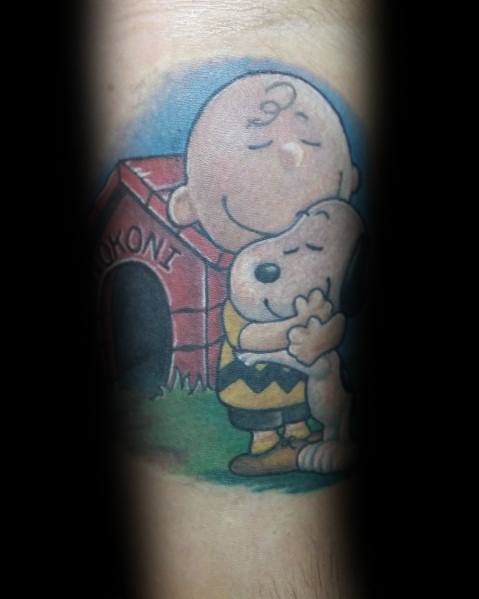Colorful Charlie Brown and Snoopy tattoo featuring a heartfelt hug in front of Snoopy’s red doghouse, symbolizing love and friendship.