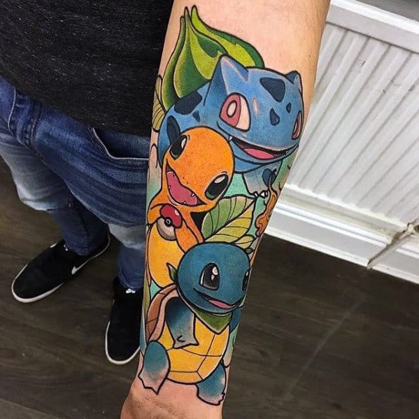 Colorful forearm tattoo featuring cheerful versions of Bulbasaur, Charmander, and Squirtle with bold outlines and leafy accents.