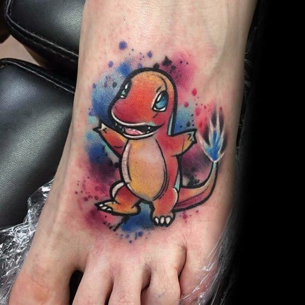 Vibrant Charmander tattoo on foot with watercolor splashes in blue and pink, featuring a bright blue flame on its tail.